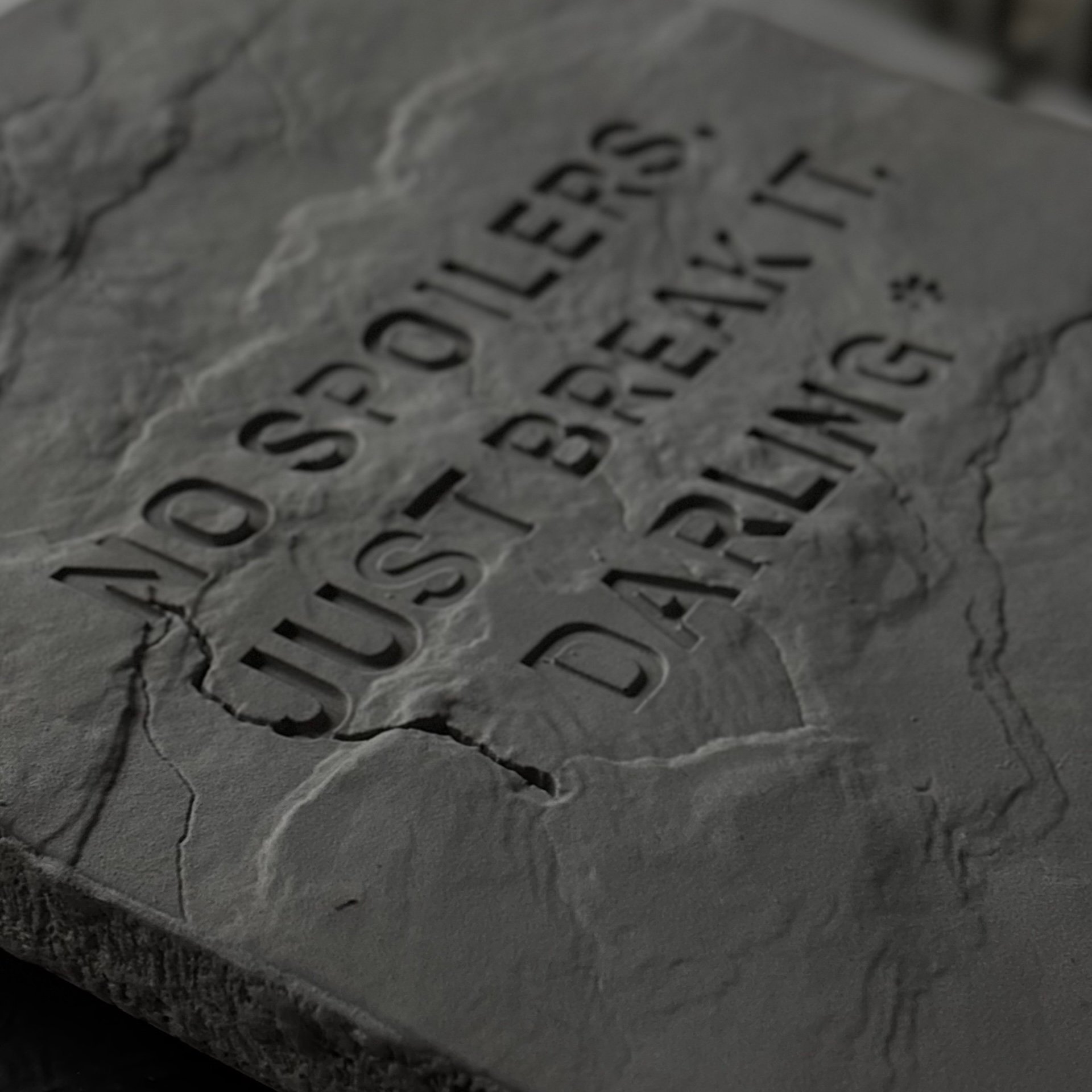 Вдавленная надпись на гипсовой плитке с фактурой камня крупным планом